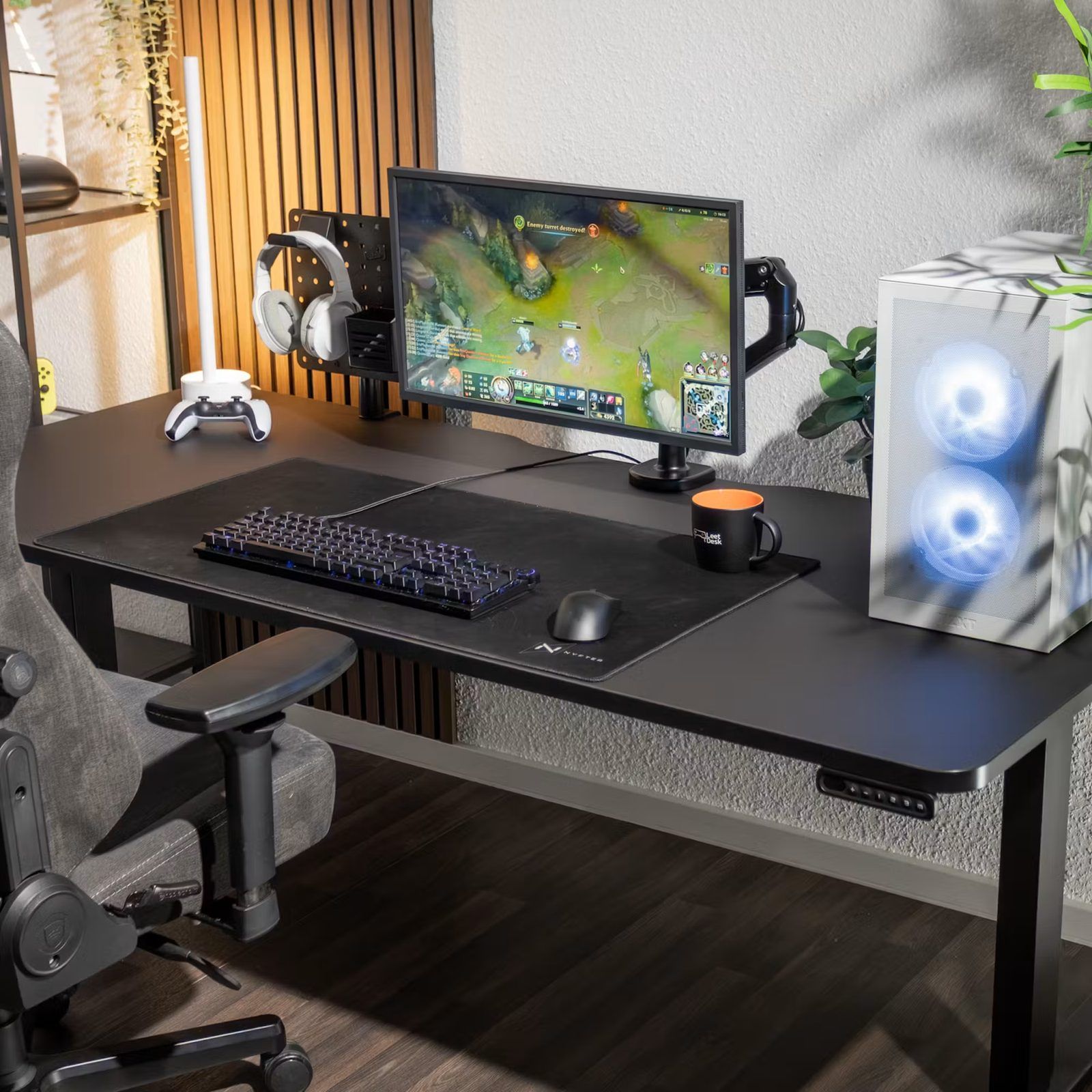 LeetDesk height-adjustable desk in black, set up with a monitor arm, mechanical keyboard and PC tower