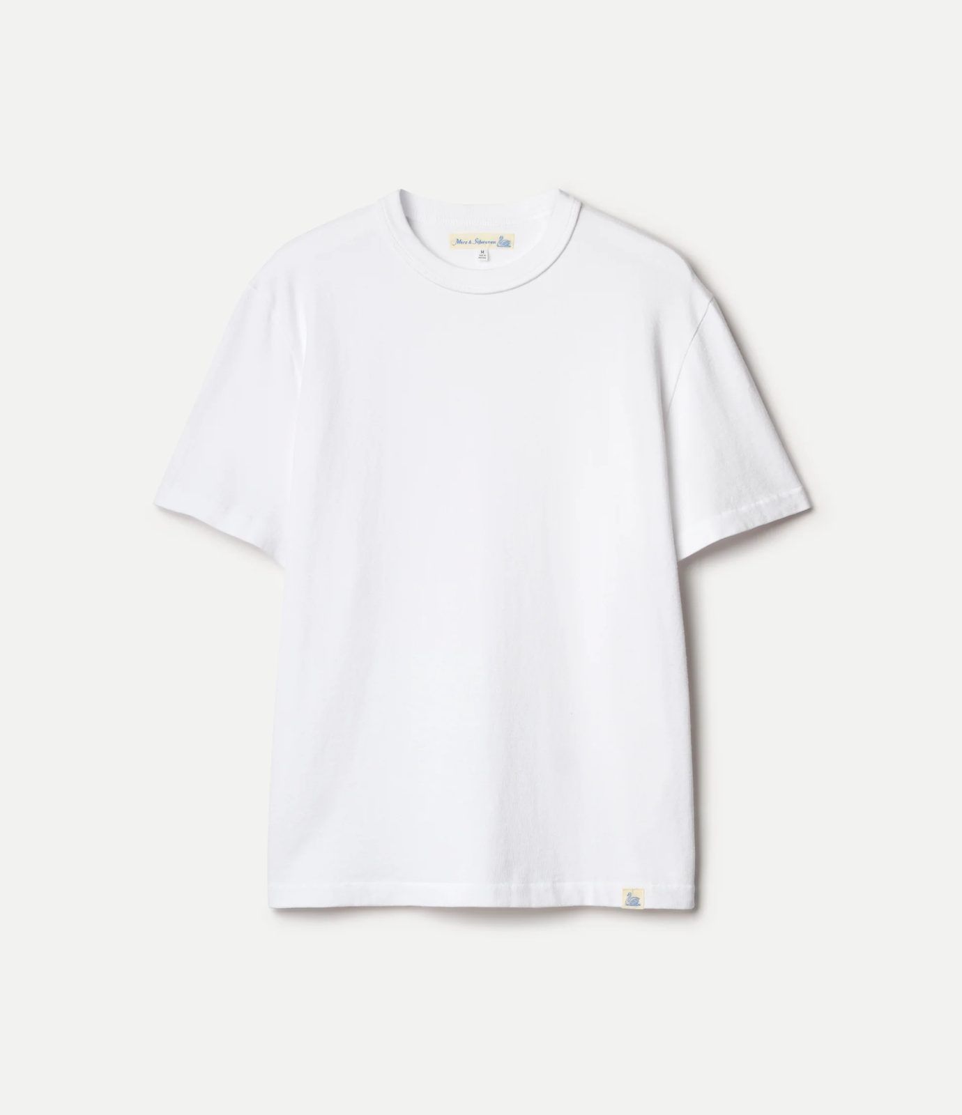 White Merz t-shirt photographed flat showing the woven neck label with the swan, the size tag and the small swan flag stitched at the hem