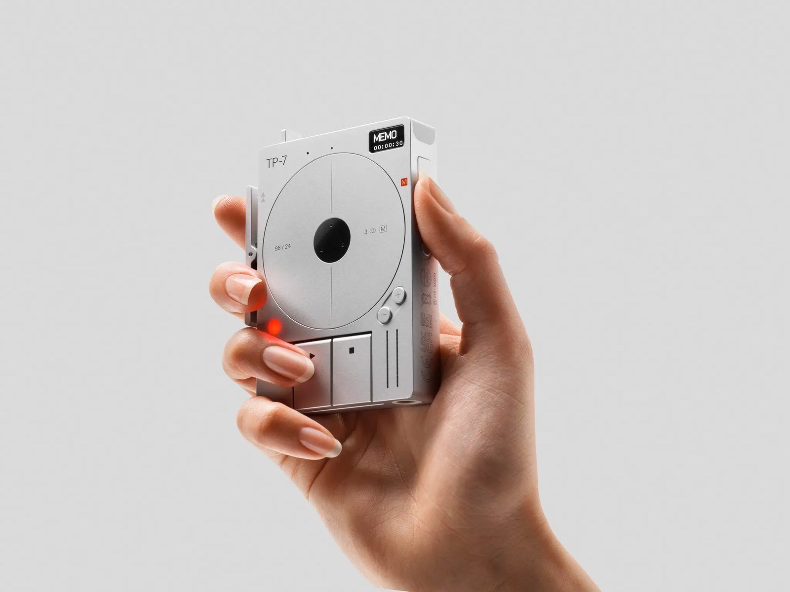 A hand holding the aluminium TP-7, which fits within the palm, thumb near the reel