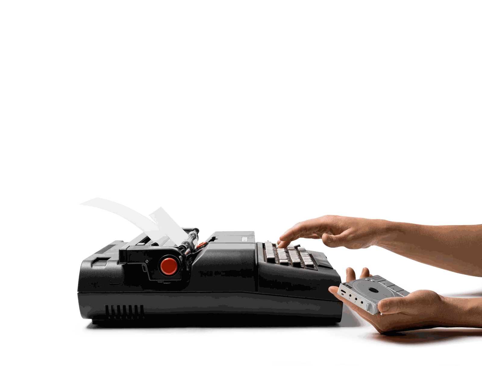 Hands typing on a black vintage typewriter, with the TP-7 lying on the desk in front of it