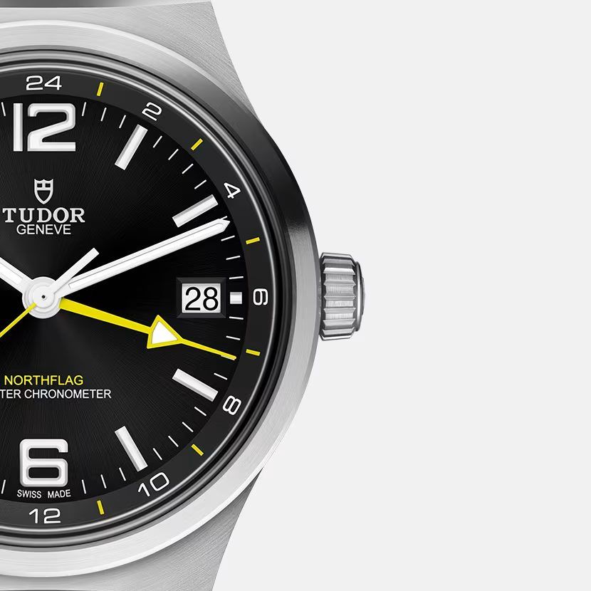Close view of the Northflag dial showing the yellow arrow GMT hand, the date at three and the fluted screw-down crown