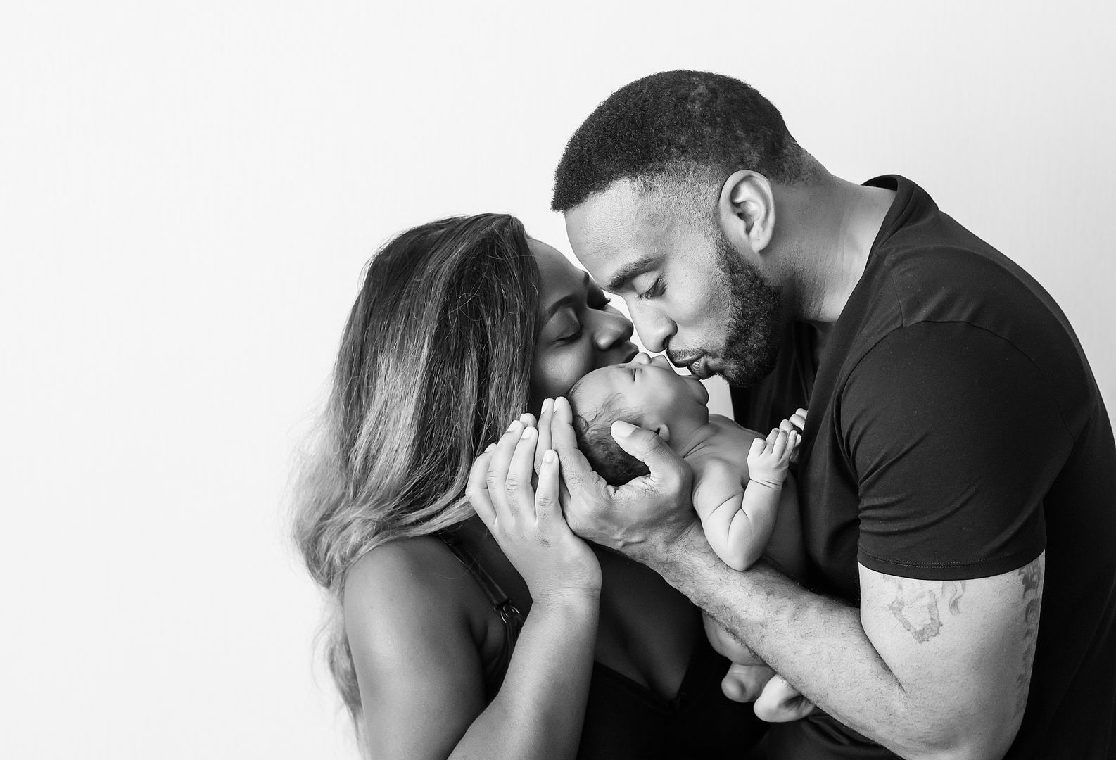 Parents kissing newborn baby together