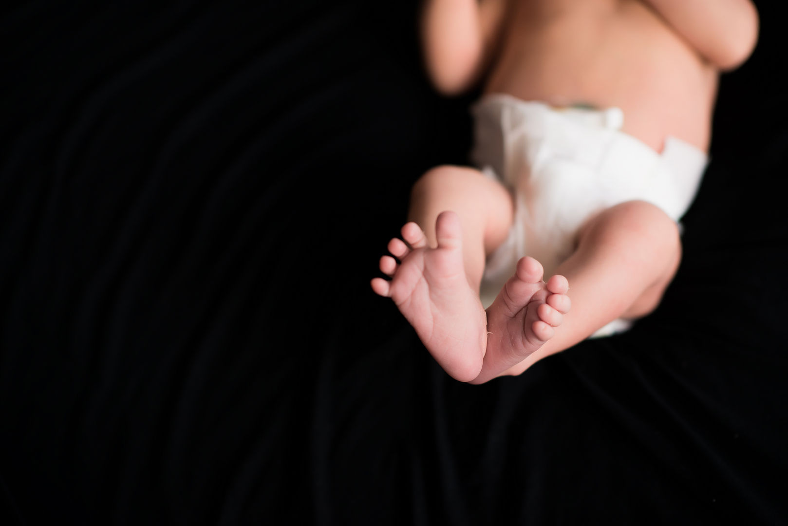 Tiny newborn feet on black background