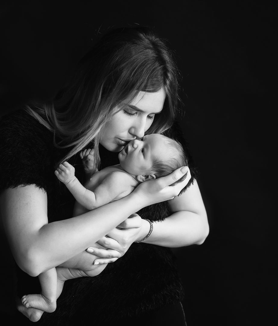 Mother holding newborn baby against dark background