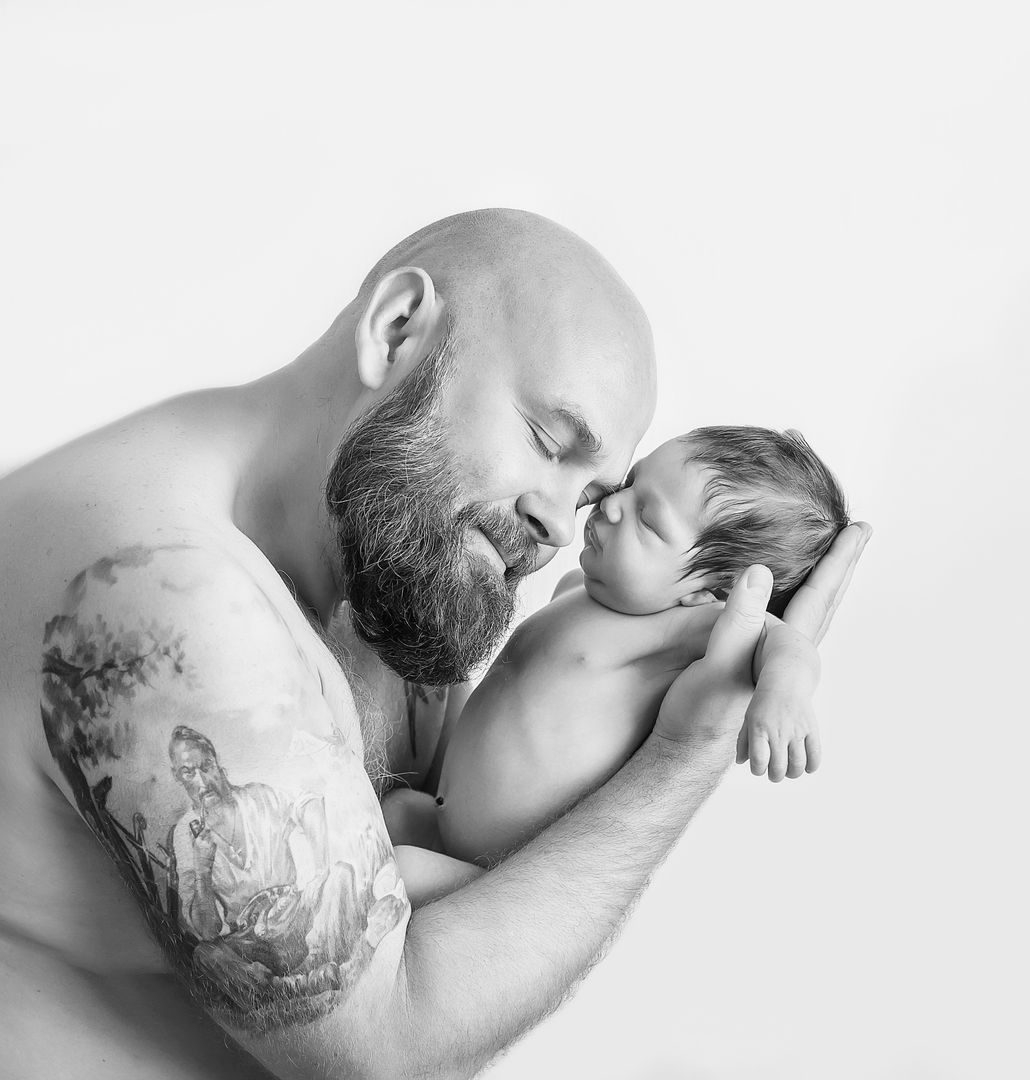 Father holding newborn baby close in black and white