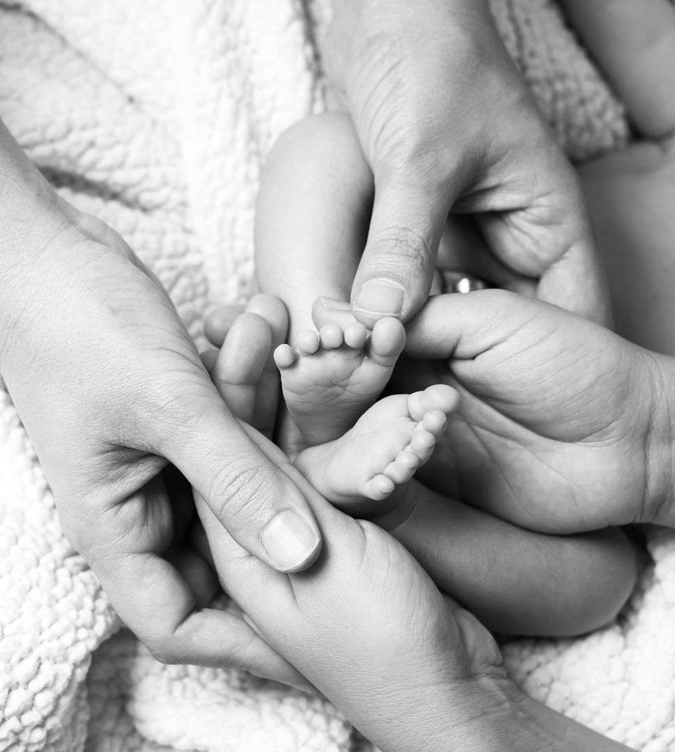 Tiny newborn feet held in parent's hands