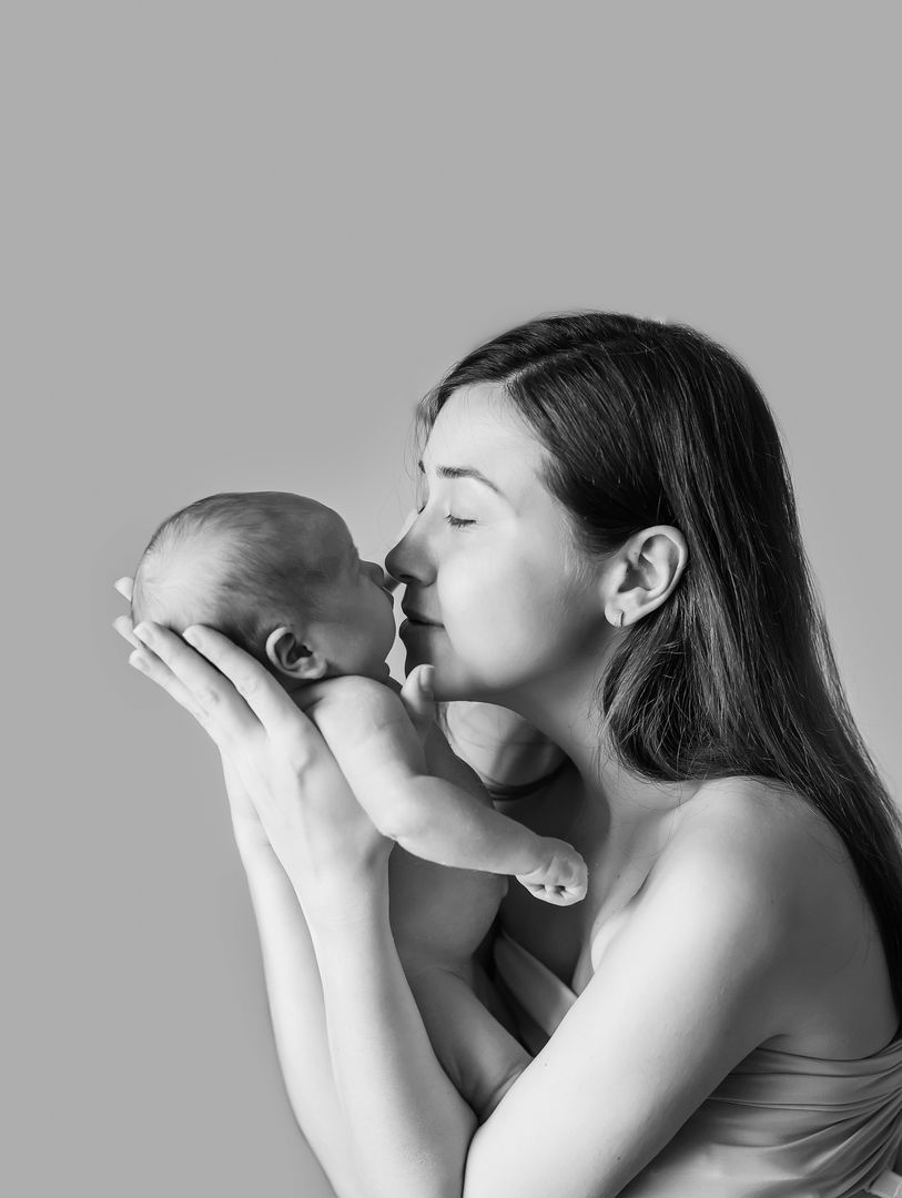 Mother kissing newborn baby in black and white