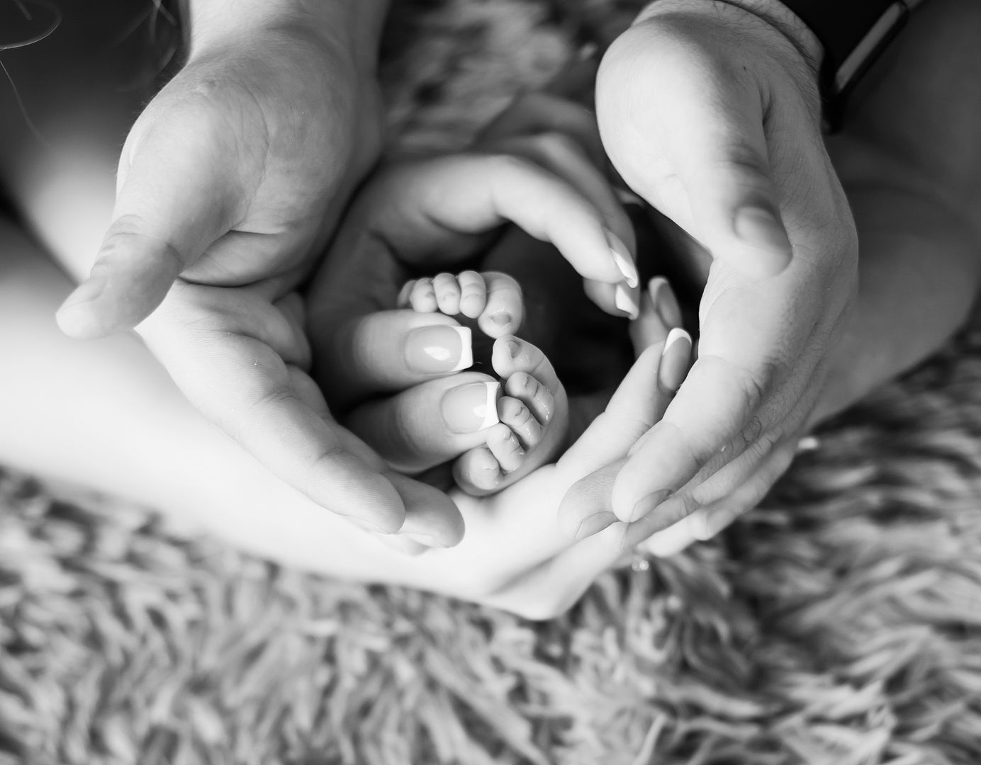 Baby feet framed by parents' hands forming a heart