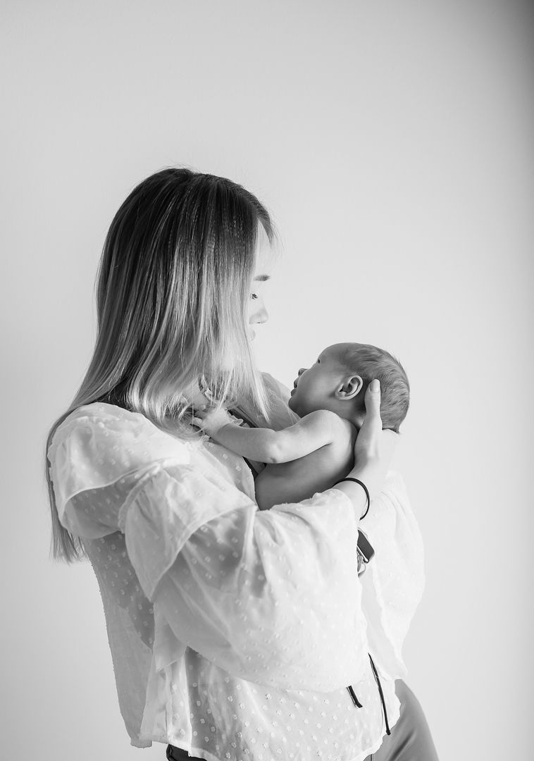 Mother holding newborn baby vertically in black and white