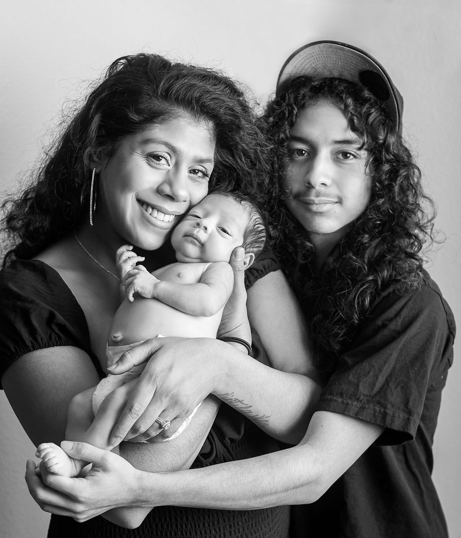 Mother and siblings embracing newborn baby