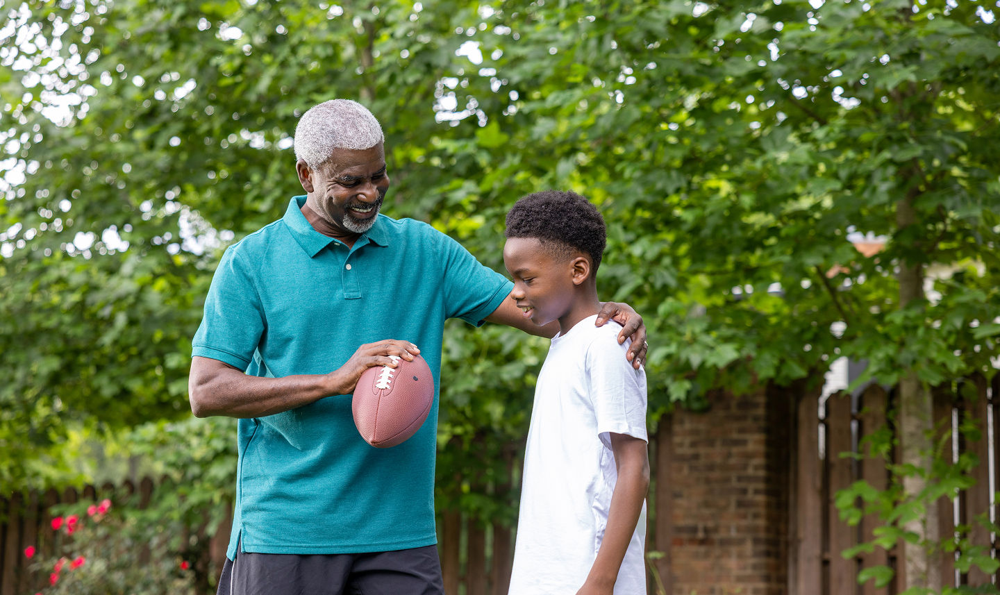 Grandpa and grandson playing football outside