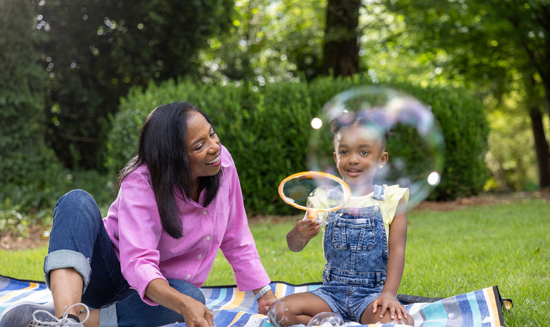 Grandma and granddaughter blowing bubbles outside