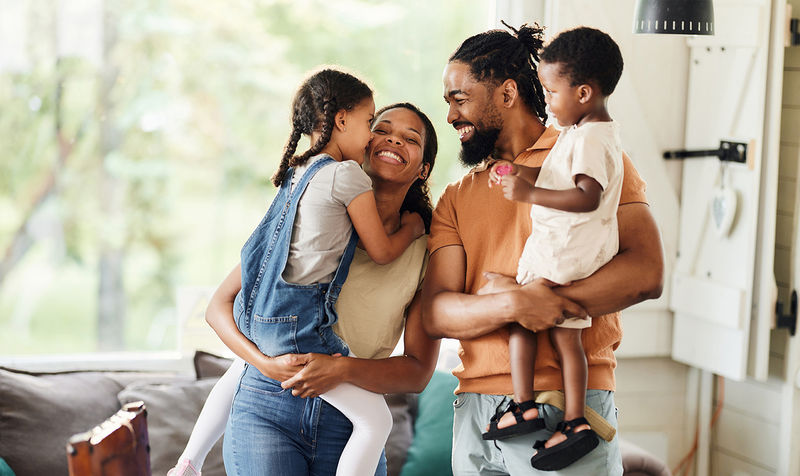 A father and mother each holding one of their two young children