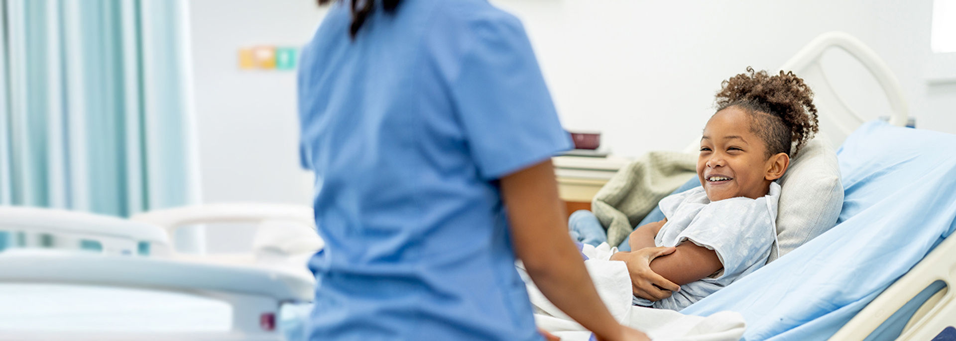 A patient sitting in a hospital bed smiling at a nurse.