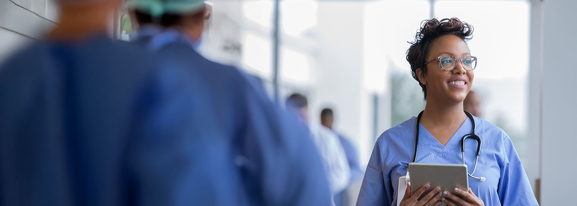 A Nurse wearing a stethoscope, looking into the distance.