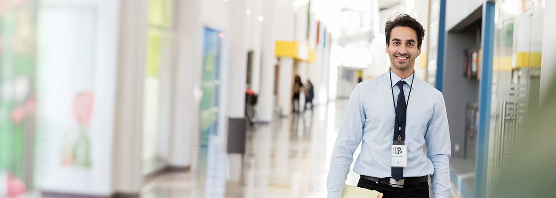 A man with a credential lanyard smiling at the camera