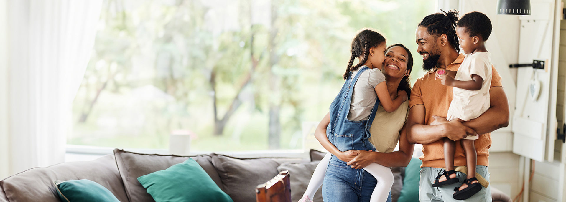 A father and mother each holding one of their two young children.