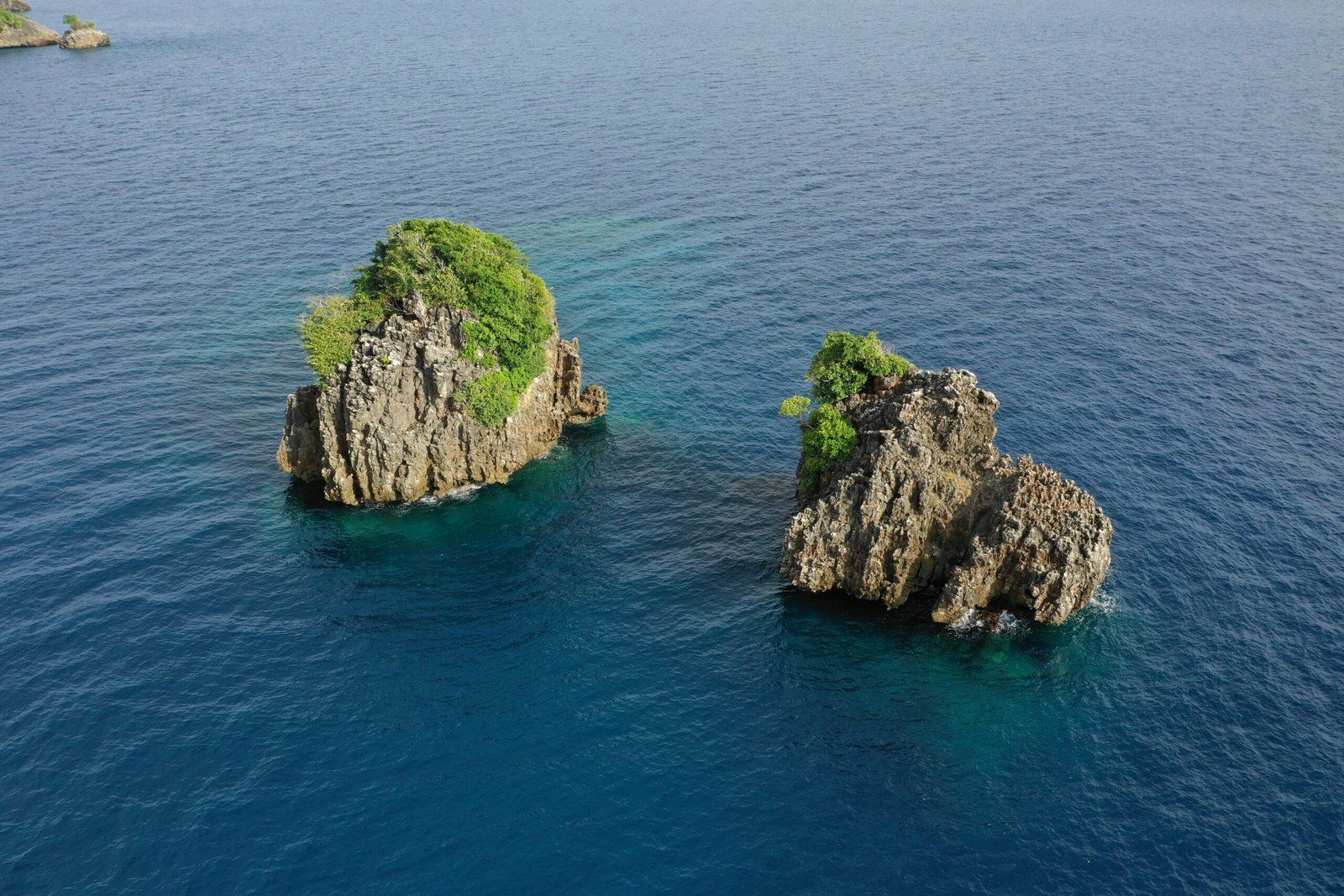 A stunning aerial shot of two lush rock formations in the vibrant blue waters of Raja Ampat, Indonesia.