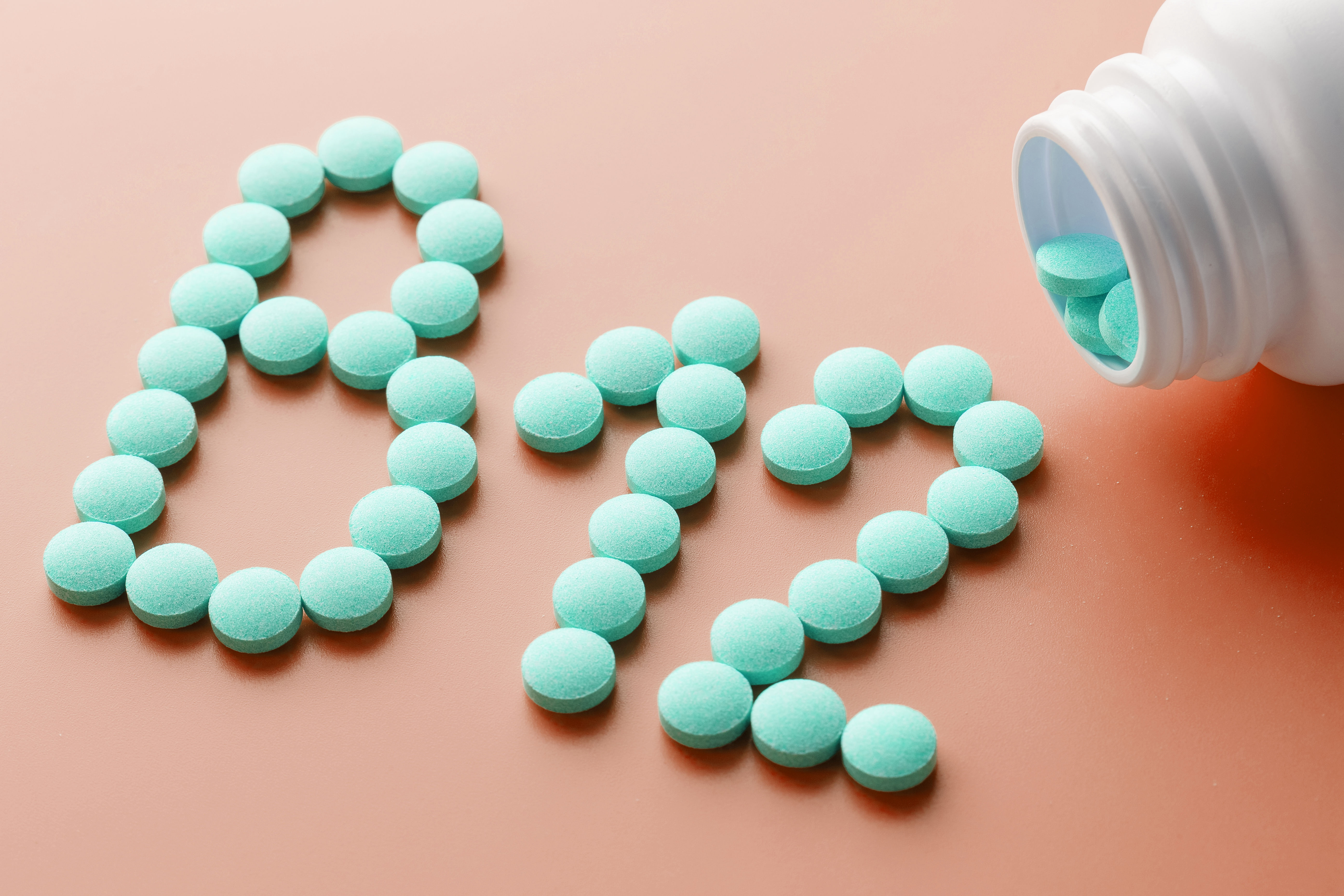Vitamin B12 tablets poured out of a jar, representing the increased B-vitamin demand during breastfeeding that can contribute to postpartum hair and energy symptoms if left unaddressed