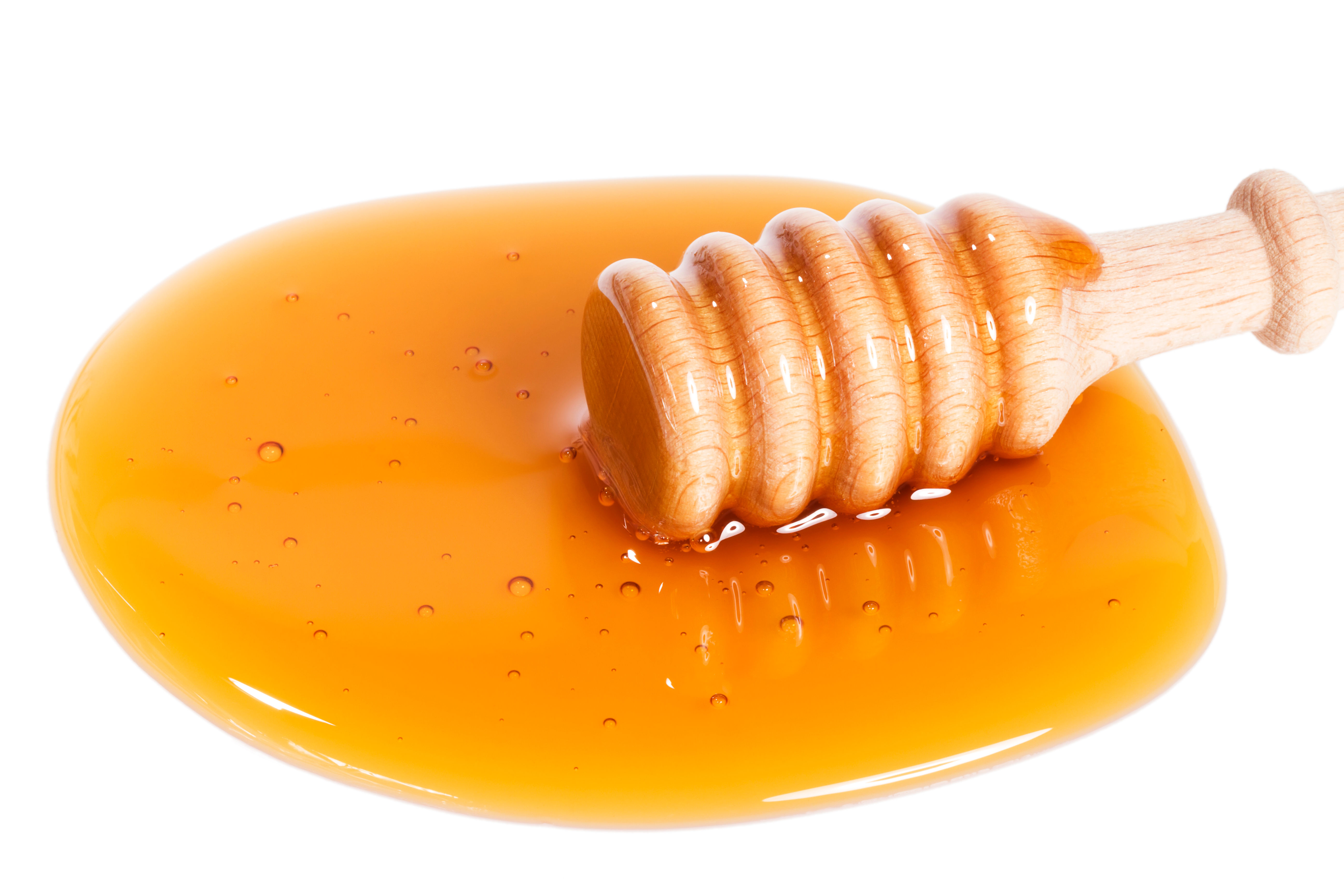Honey dripping from a wooden spoon into a jar of honey — natural sweeteners like honey, maple syrup, and agave nectar are still classified as added sugar even when marketed as wholesome alternatives