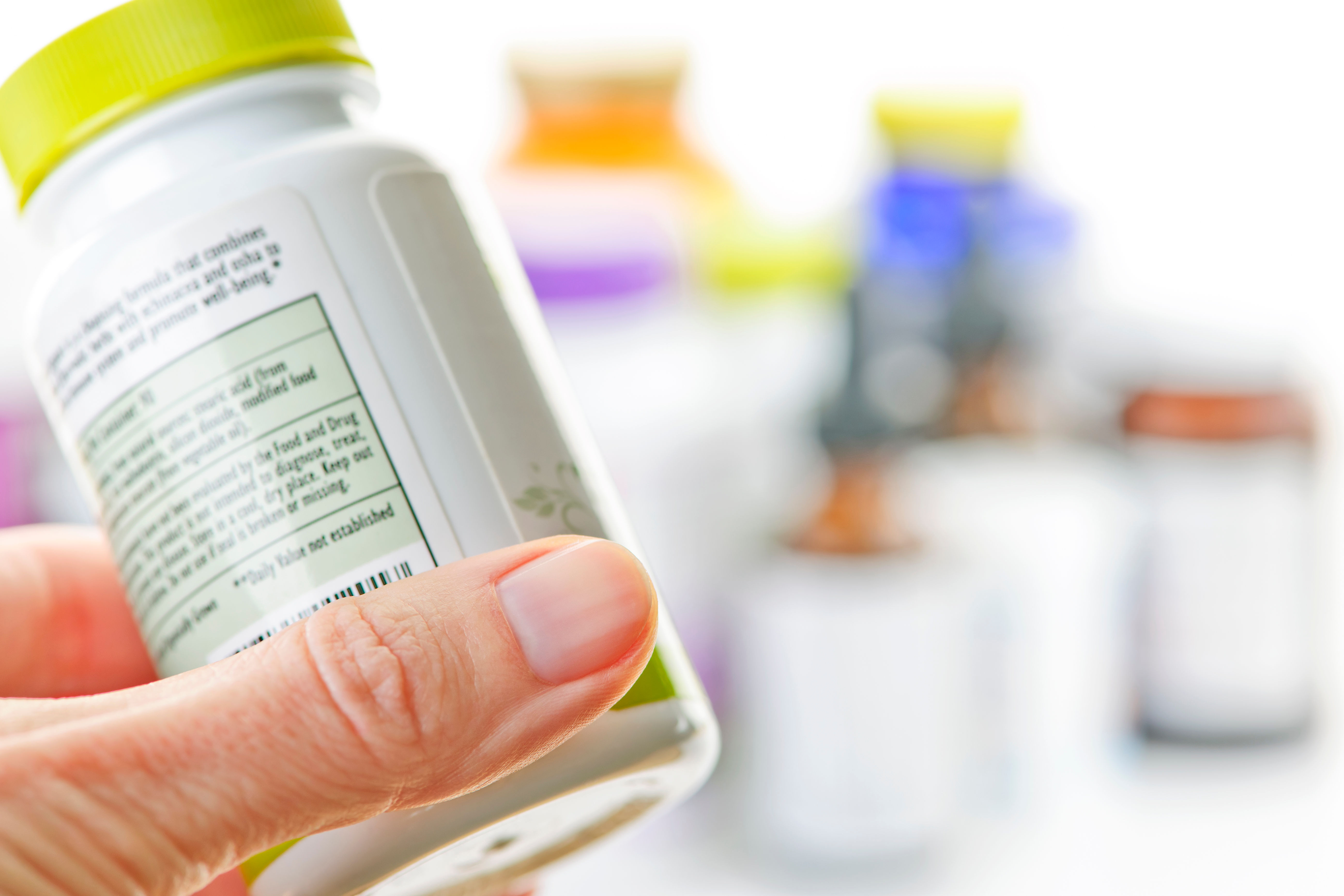 Hand holding a medicine bottle — multivitamins are regulated in the United States as dietary supplements under DSHEA, a distinct legal category from both foods and drugs