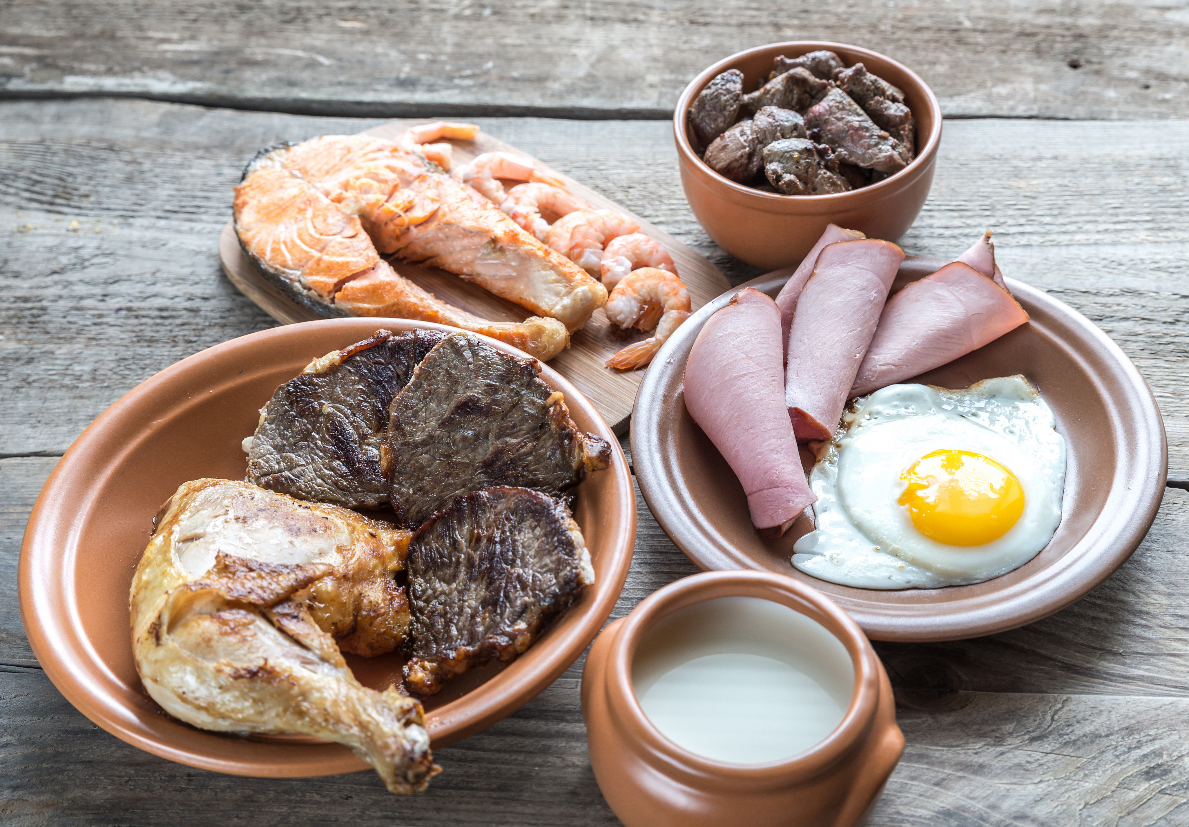 Protein-rich foods on a wooden background representing the importance of adequate protein intake during the ages 50-59 decade to combat sarcopenia and muscle loss