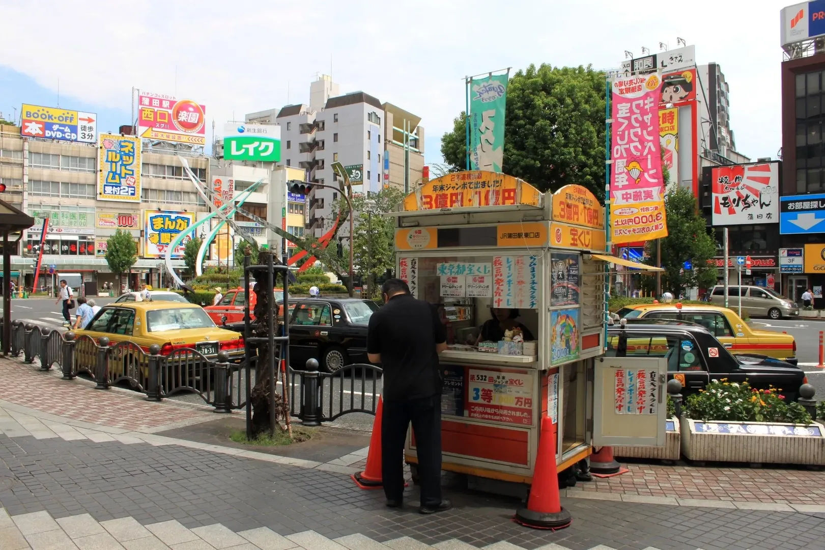 Kolorowy kiosk z gazetami w Tokio, Japonia, z osobą stojącą obok, a w tle samochody i budynki miejskie