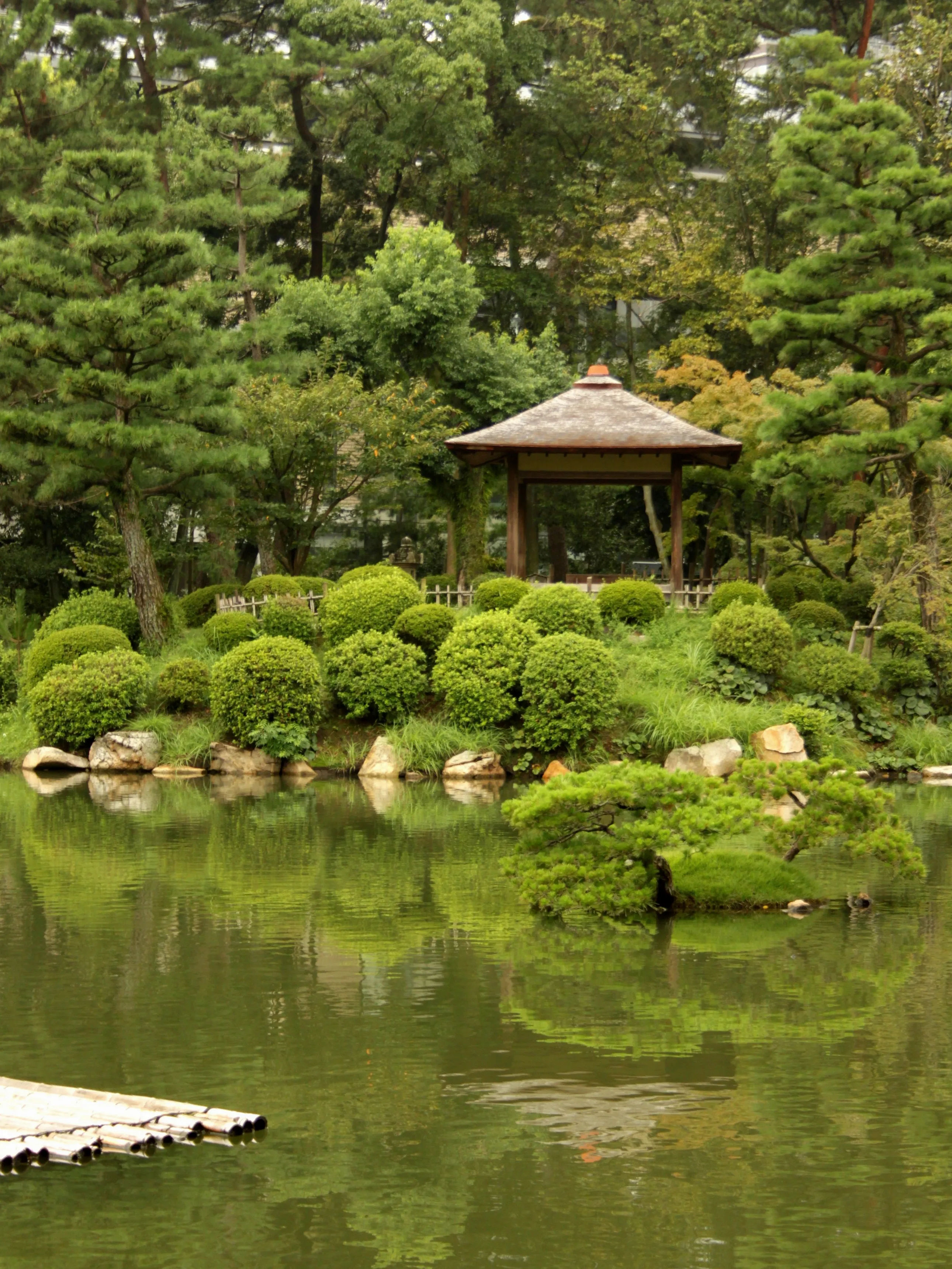 A serene view of a traditional Japanese gazebo by the pond in Shukkeien Park.