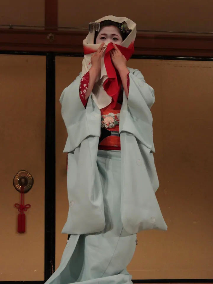 Tradycyjny japoński strój na scenie Kabuki, z czerwonym obi i delikatnymi detalami.