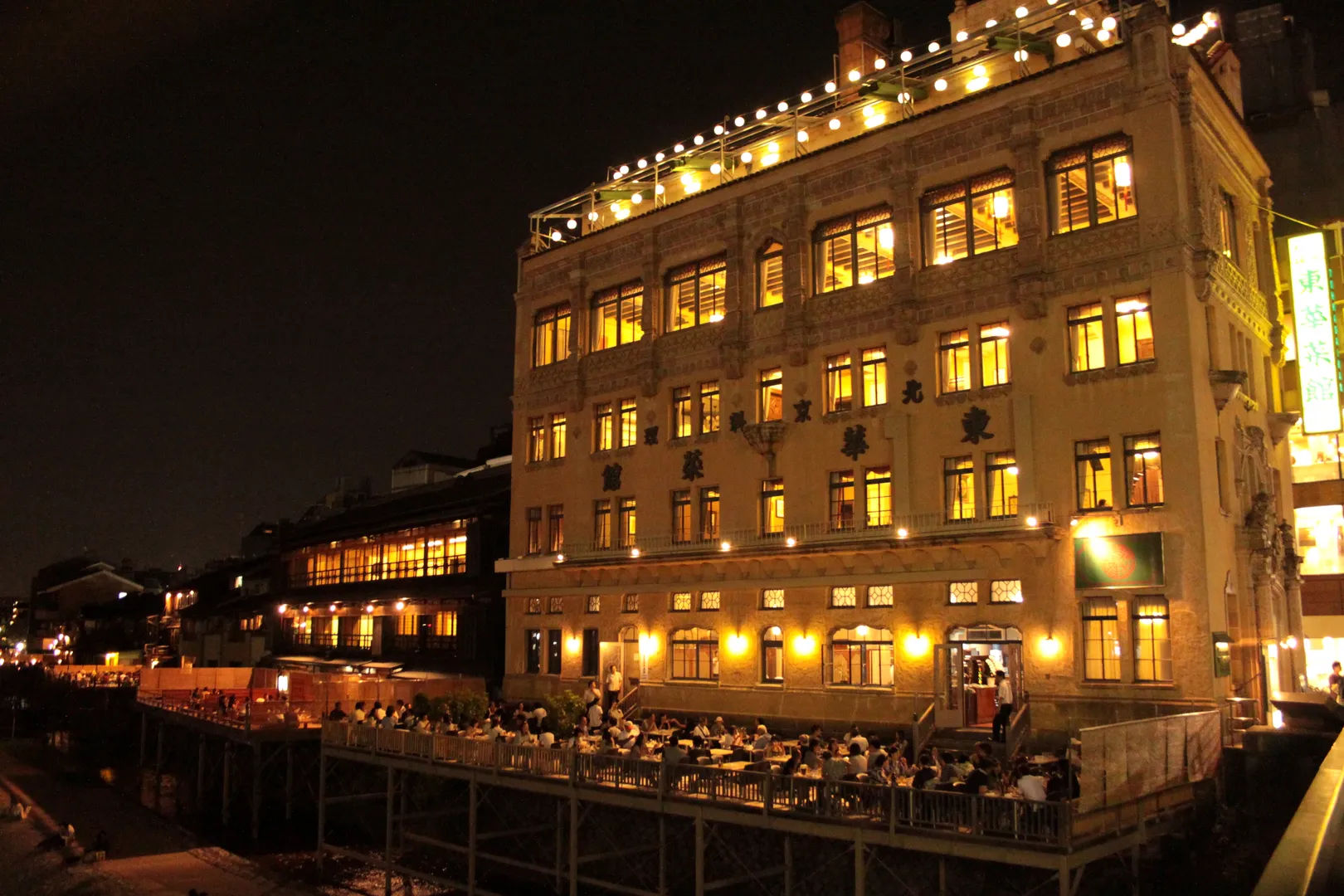 Oświetlony budynek restauracyjny z tarasami nad rzeką Kamogawa w Kioto nocą