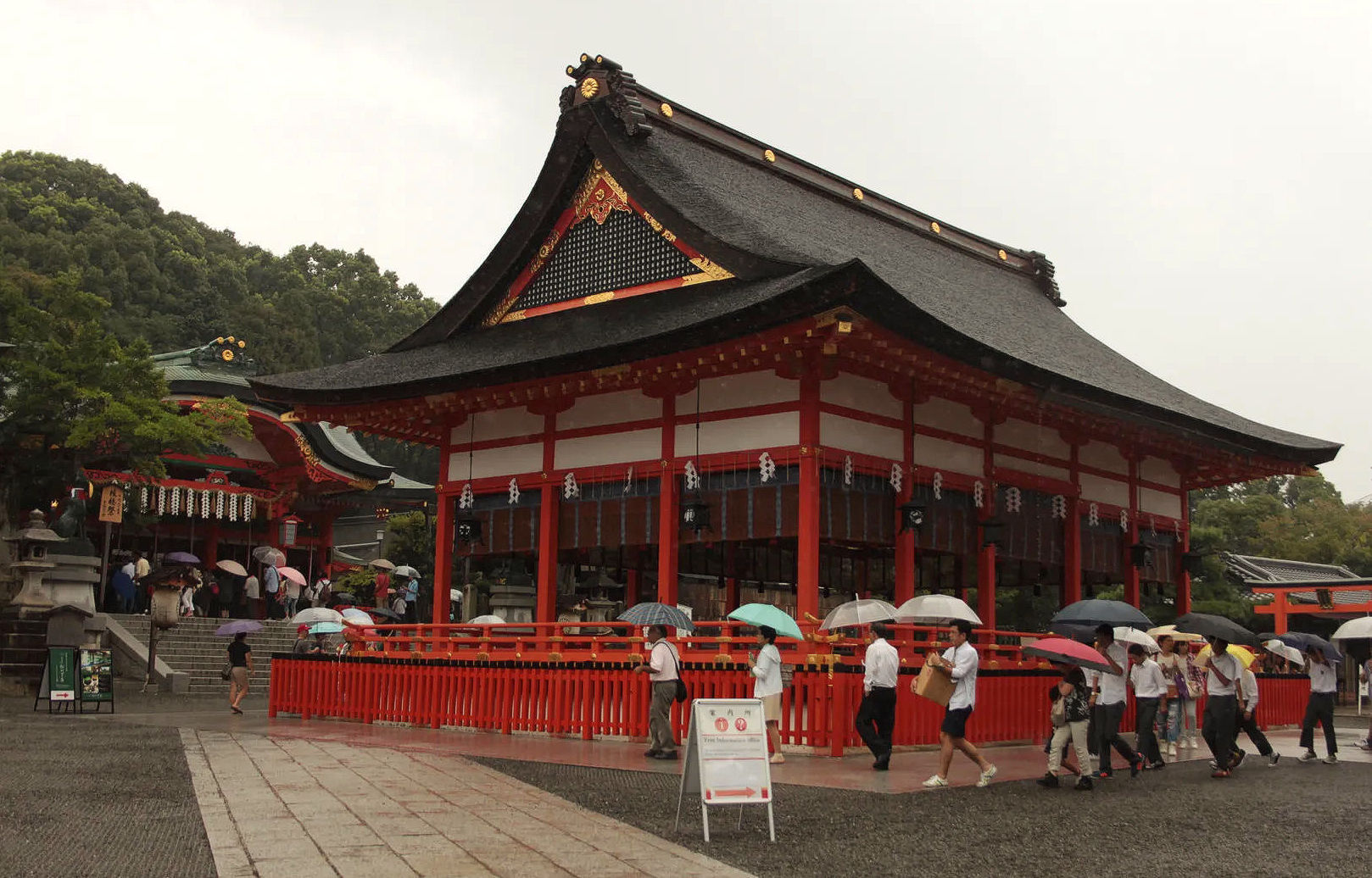 Główna sala modlitwy w Fushimi Inari Taisha otoczona odwiedzającymi z parasolami