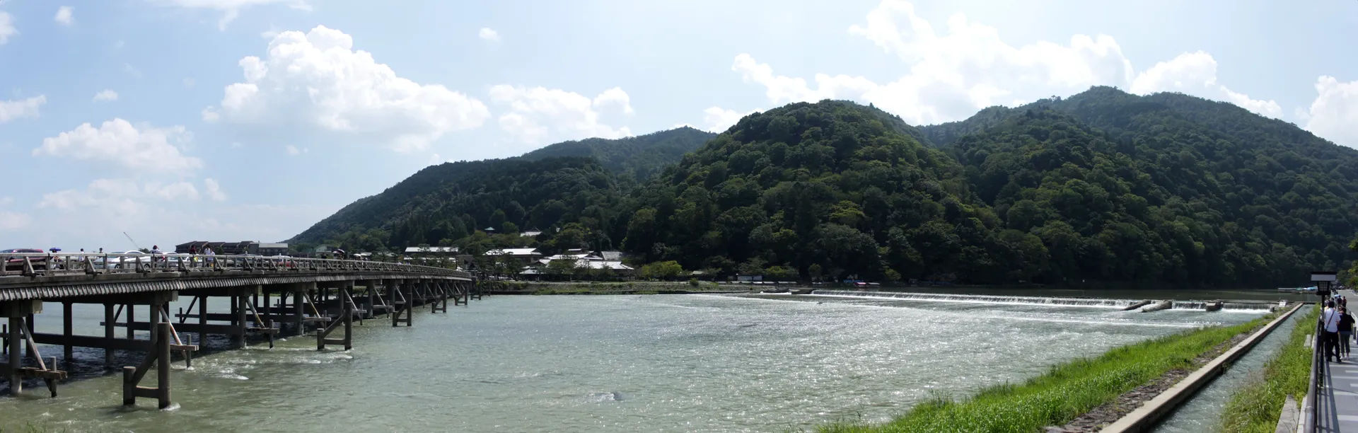 Panorama mostu Togetsukyo nad rzeką w Arashiyamie, Kioto, z górami w tle.