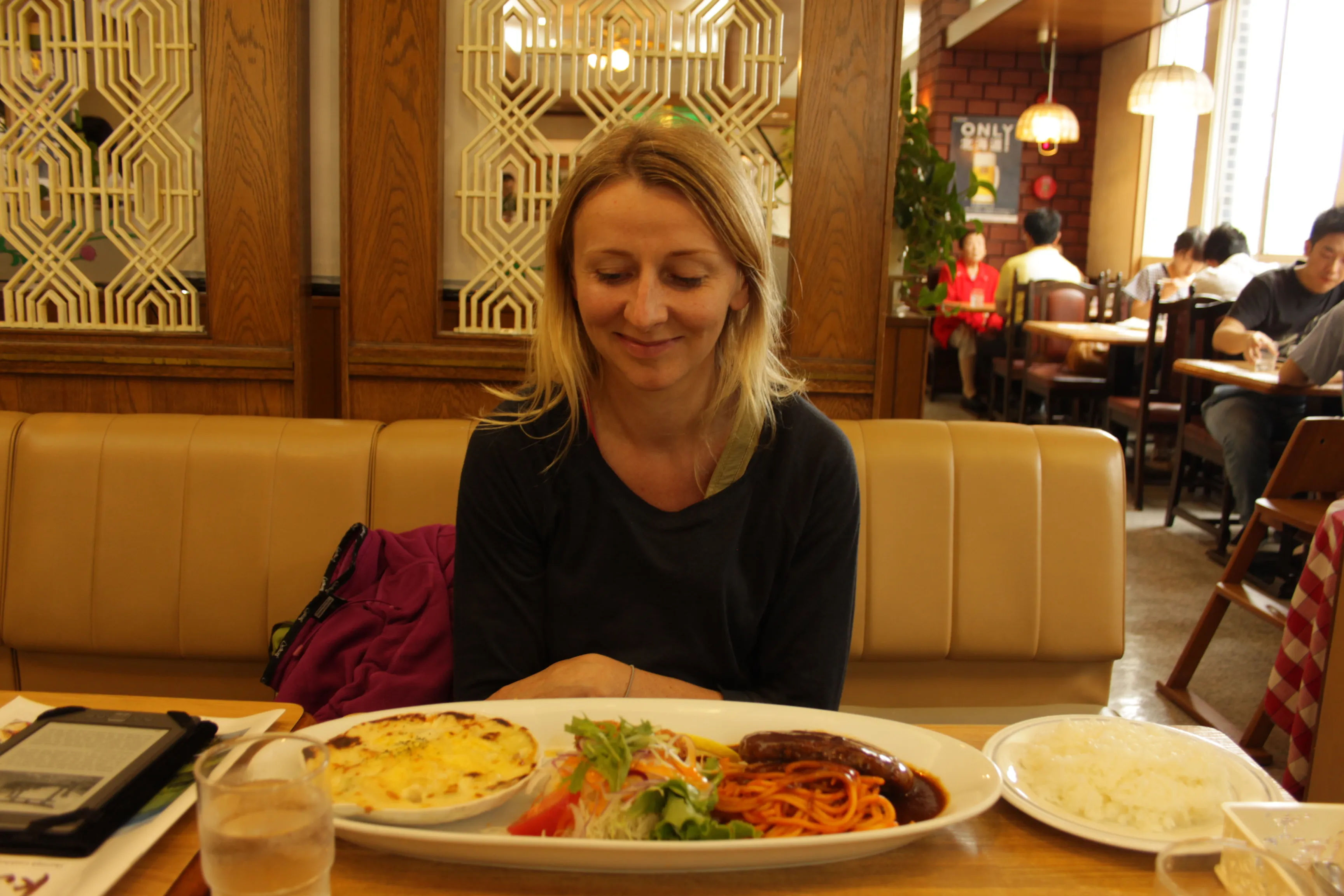 Kobieta siedząca w restauracji przed talerzem z jedzeniem