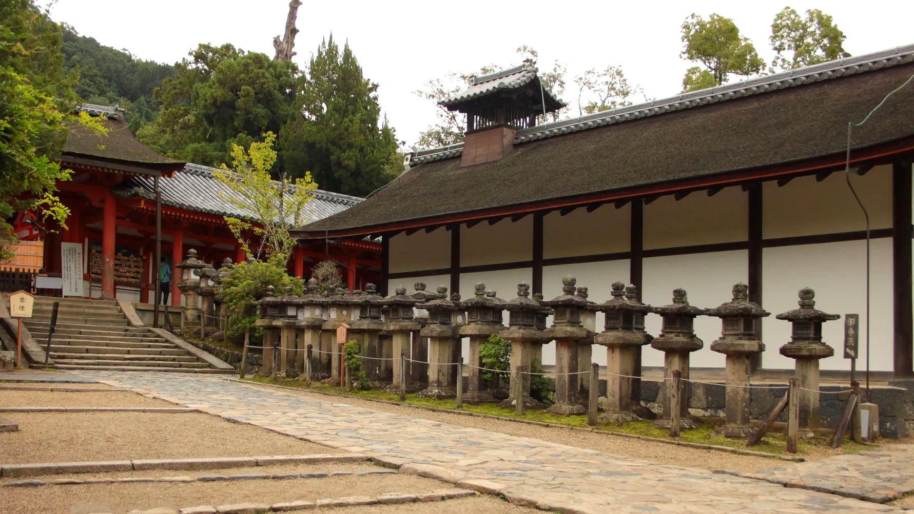 Stone lanterns lined up in front of a traditional building in Kasuga Taisha, Nara