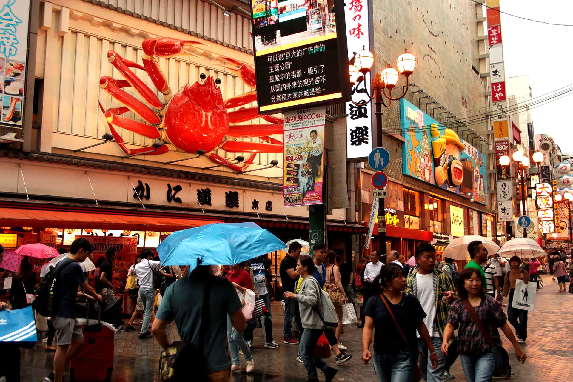 Tłum ludzi pod gigantycznym krabem na ruchliwej ulicy Dotonbori w Osace, znanej z neonów i restauracji