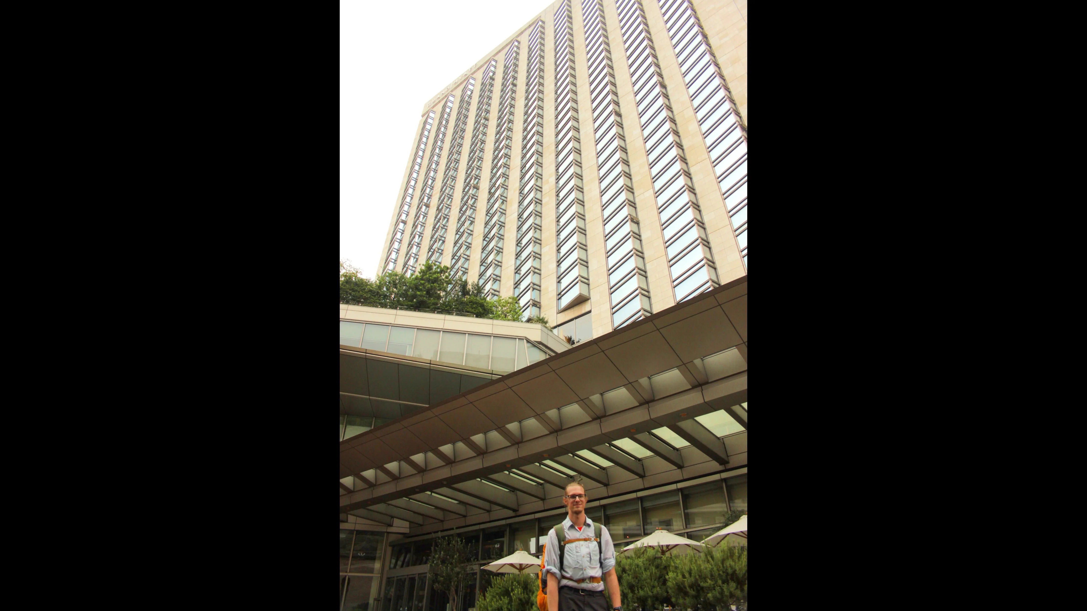Osoba stojąca przed Hotelem Hyatt w Roppongi, z widokiem na nowoczesny budynek.