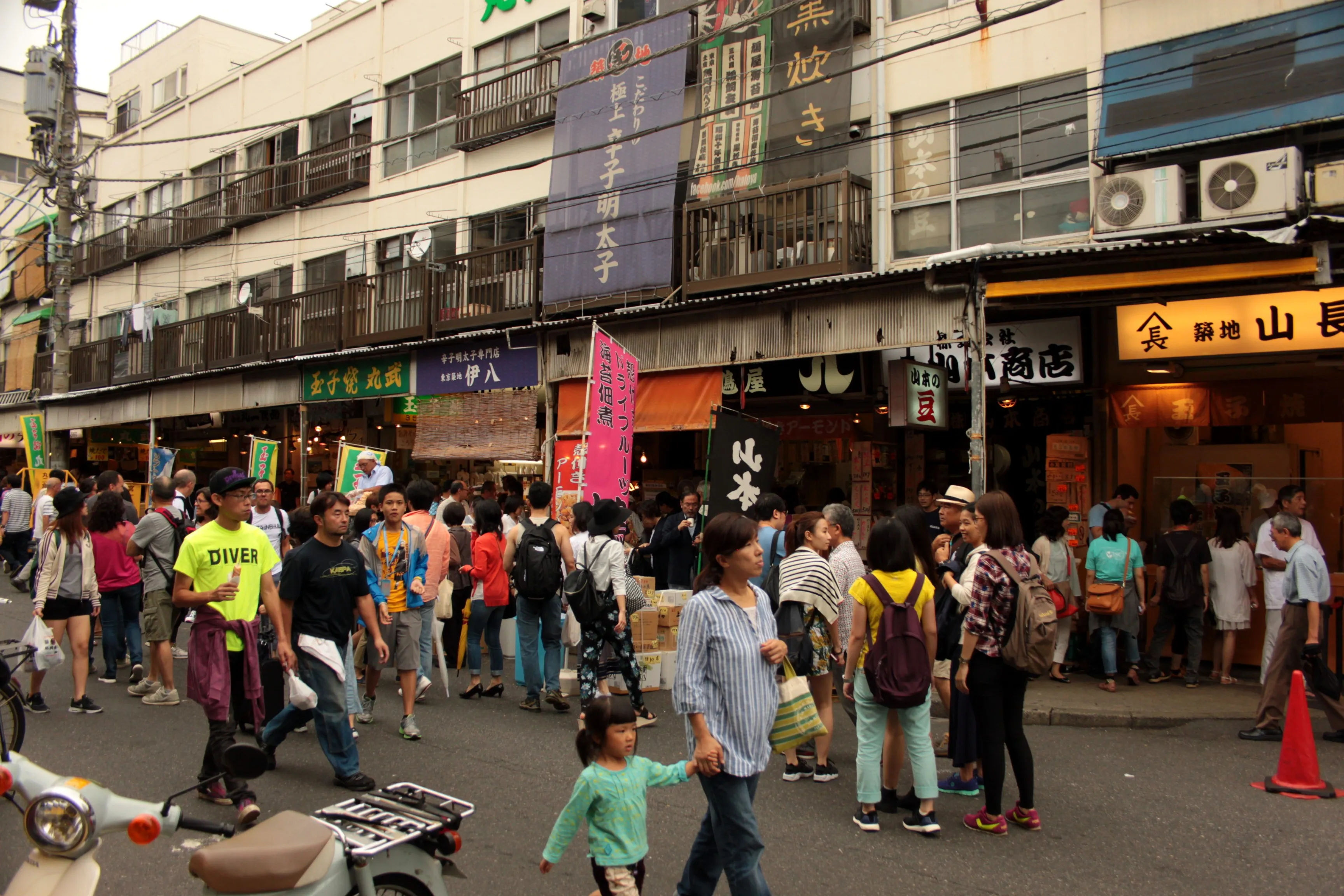 Kolejka ludzi przed restauracjami w pobliżu Tsukiji Market, czekających na wejście.