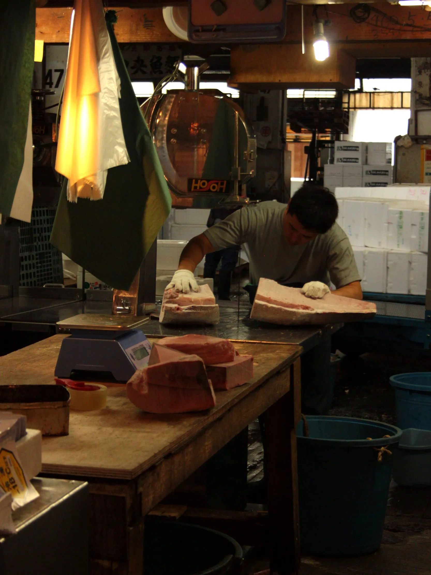 Pracownik krojący duży kawałek tuńczyka w Tsukiji Market.