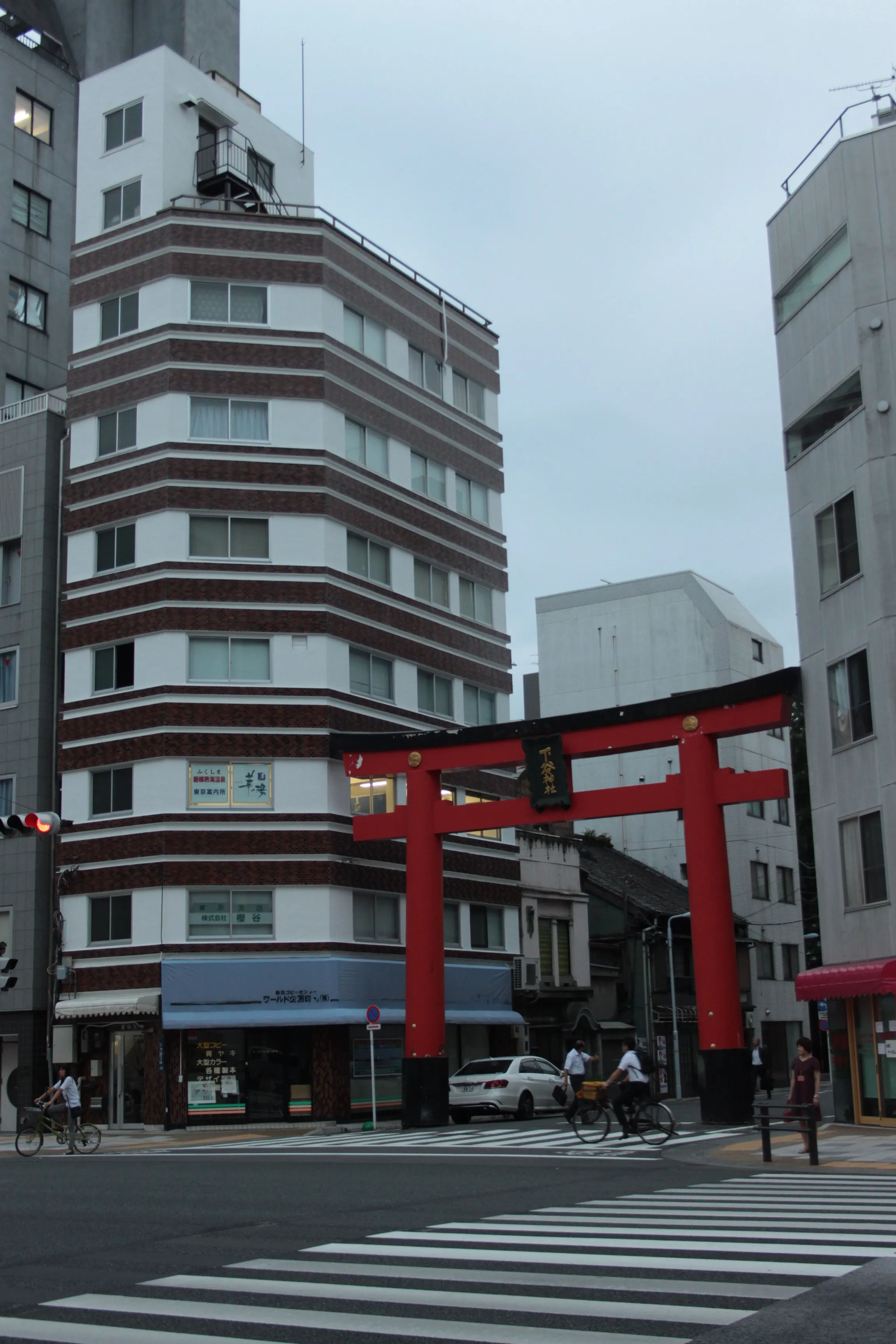 Czerwona bramka torii w dzielnicy Asakusa, na tle nowoczesnych budynków.