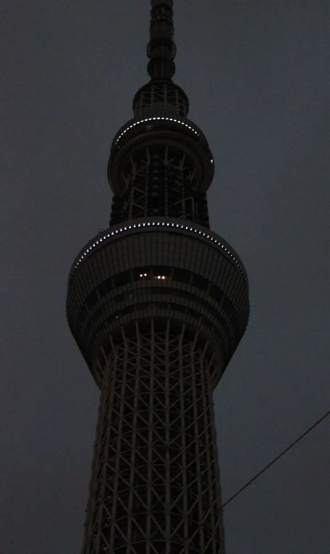 Tokyo Skytree oświetlone nocą fioletowym światłem, widok z dołu.