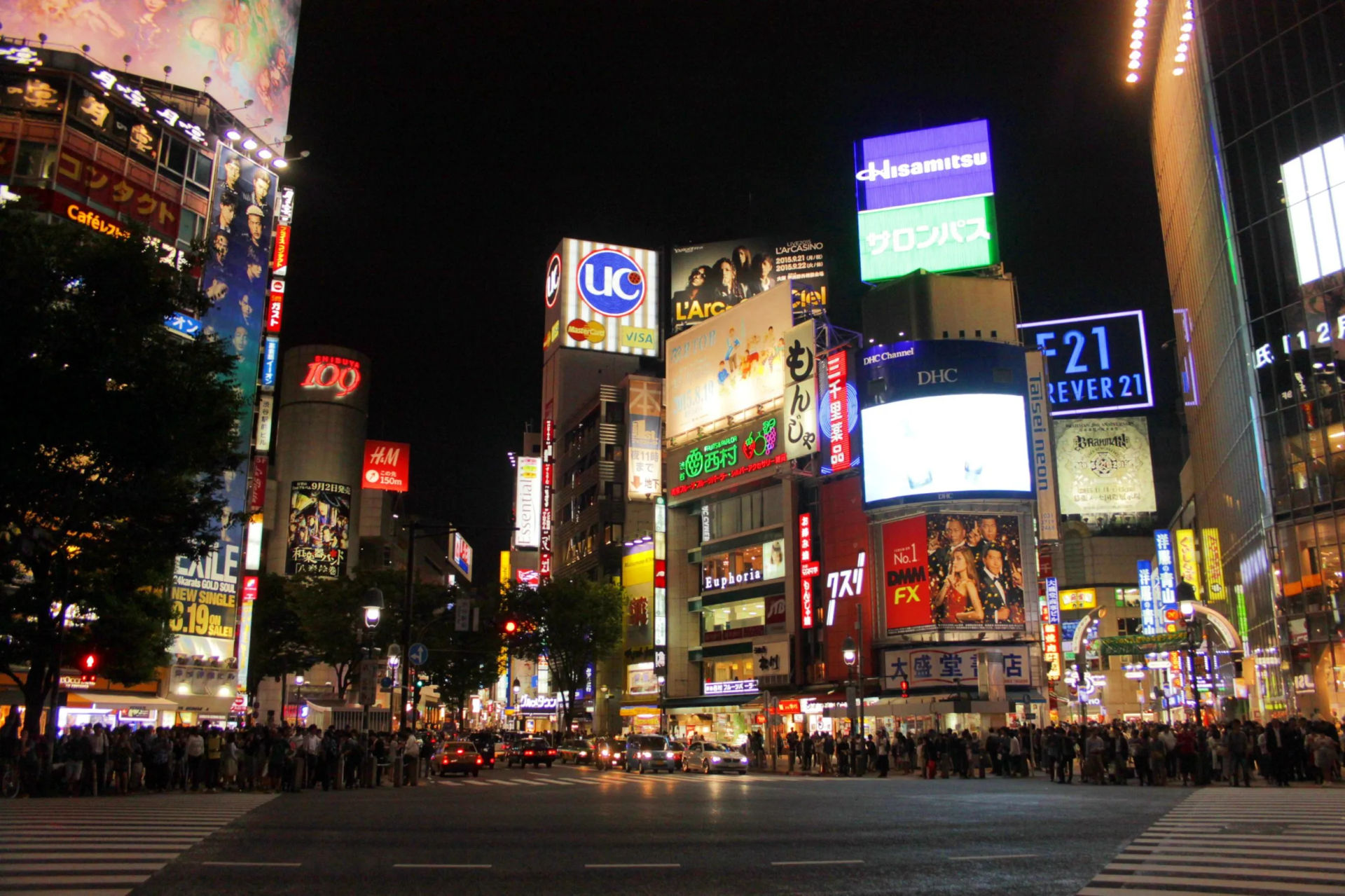Nocny widok na słynne skrzyżowanie Shibuya, otoczone neonami i reklamami.