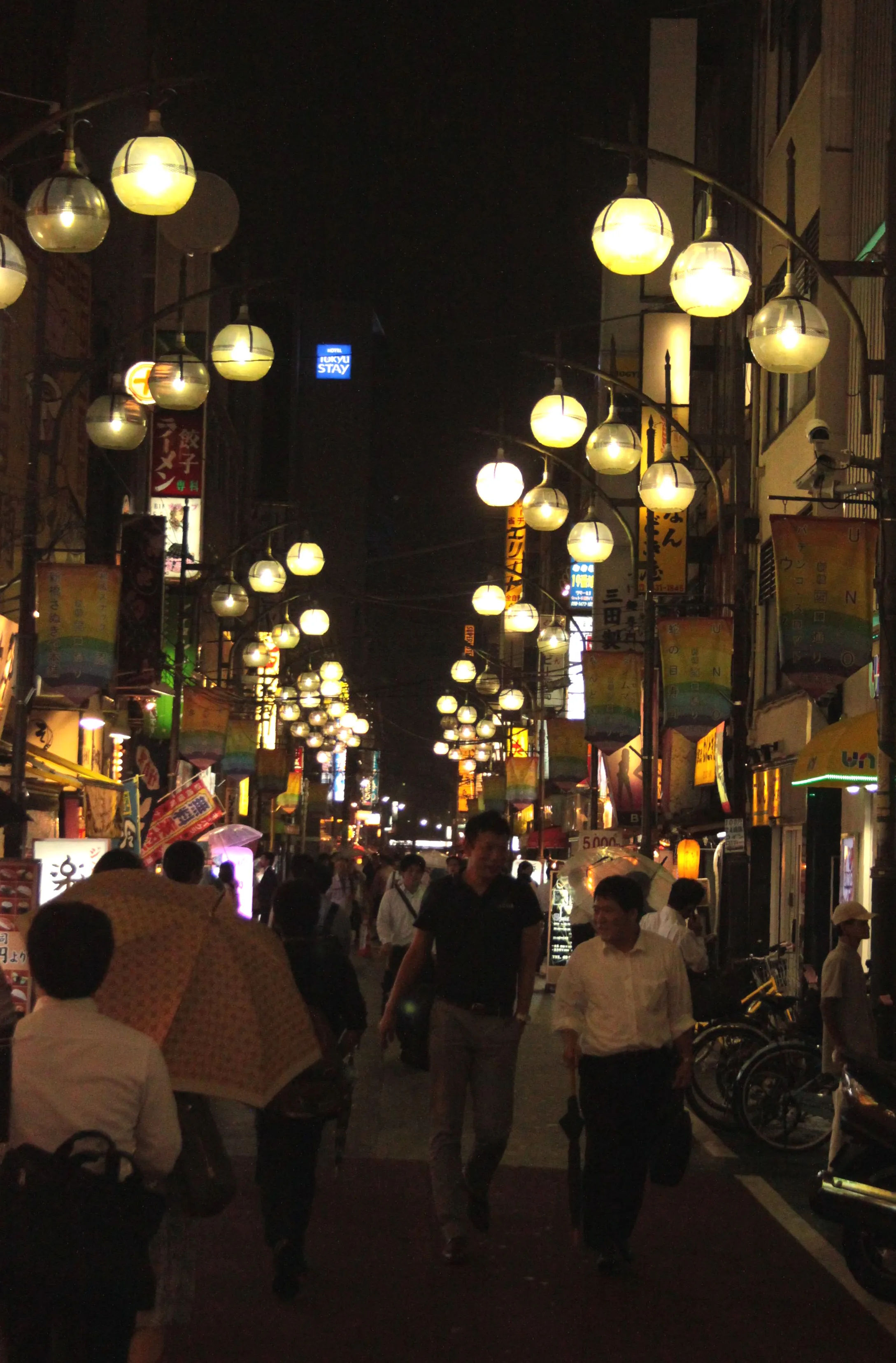 Nocny widok na ulicę w Shimbashi, ozdobioną wiszącymi lampionami i neonami.