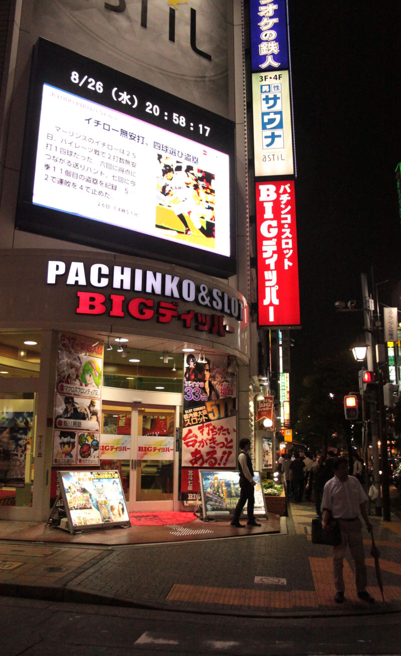 Wejście do salonu Pachinko w dzielnicy Shimbashi, otoczone neonami nocą.
