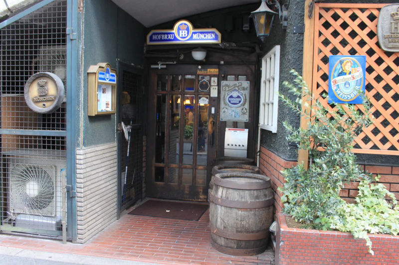 Zamknięte drzwi wejściowe do browaru Hofbräu München z beczką i szyldami browaru, Tokio, Japan