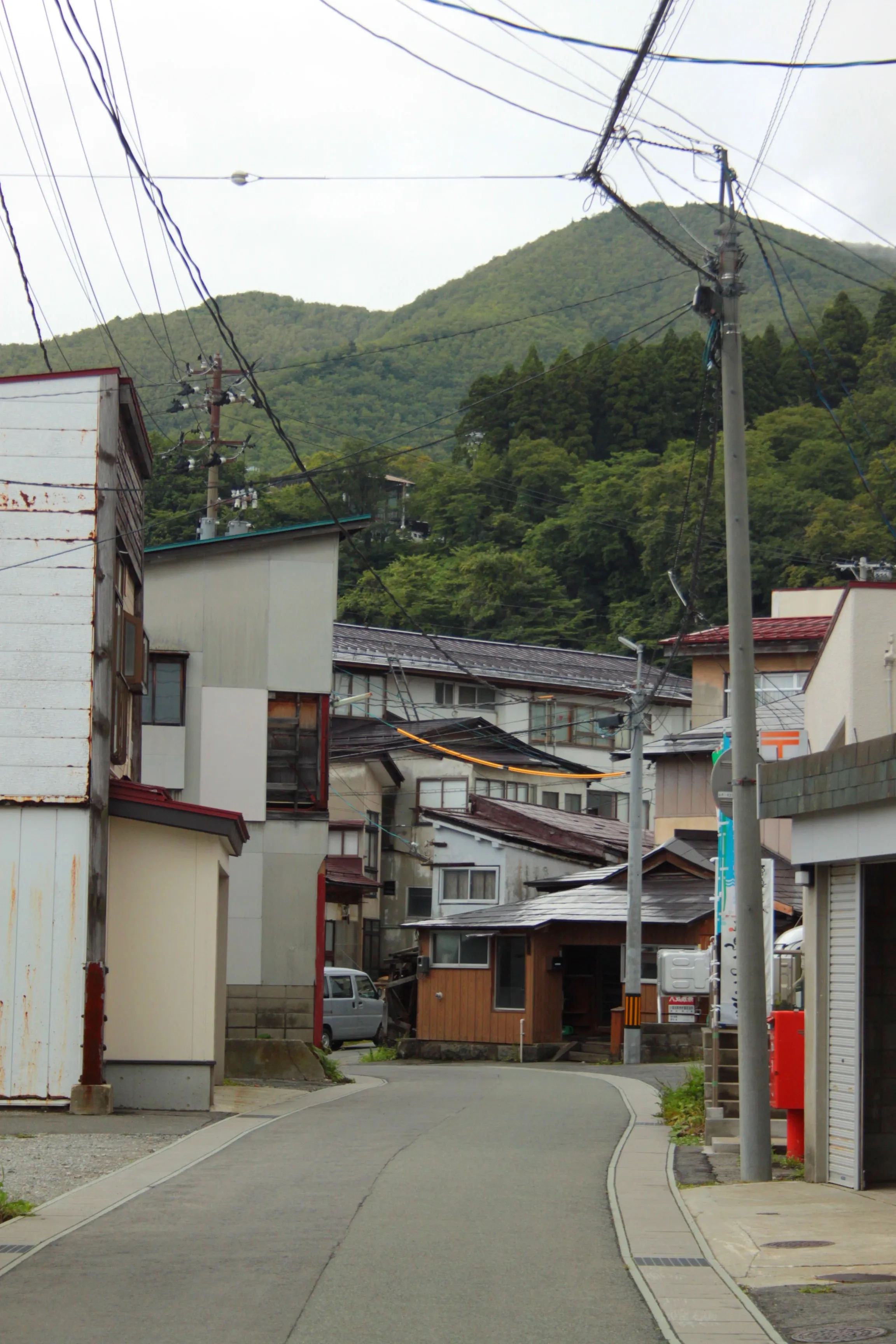 Widok na tradycyjne japońskie budynki w Zao Onsen, Japonia, otoczone górzystym terenem.