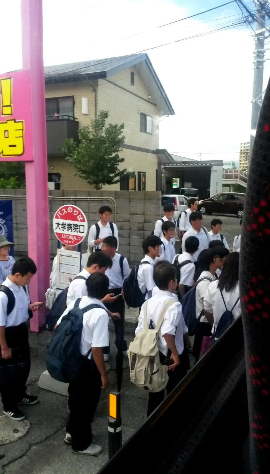 Grupa japońskich uczniów w mundurkach szkolnych stojących na przystanku autobusowym, Japonia.