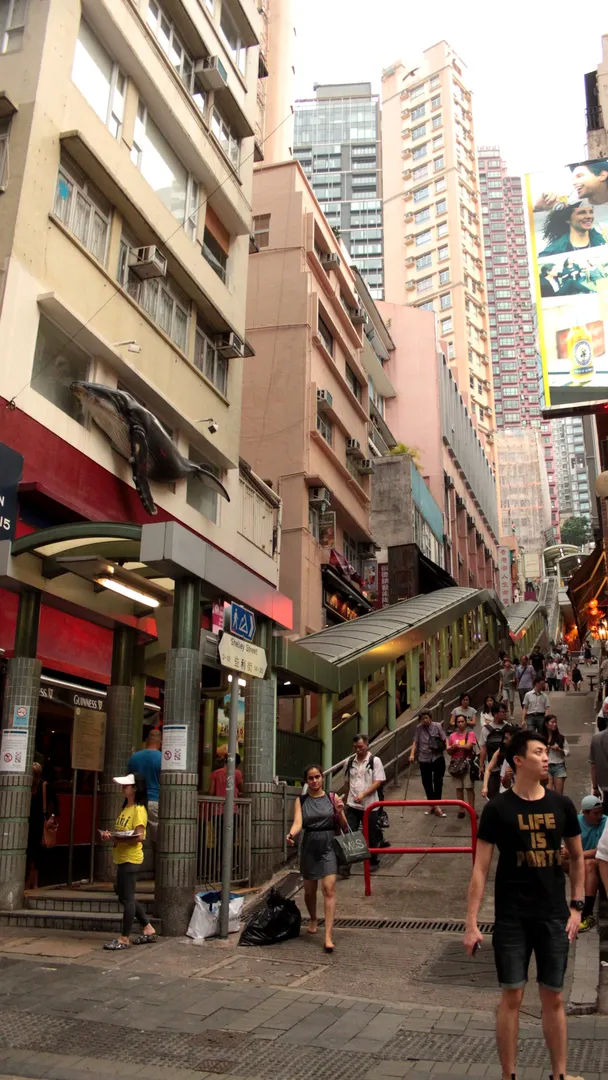 Wąska ulica z charakterystycznymi schodami i zielonymi poręczami na wyspie Hongkong