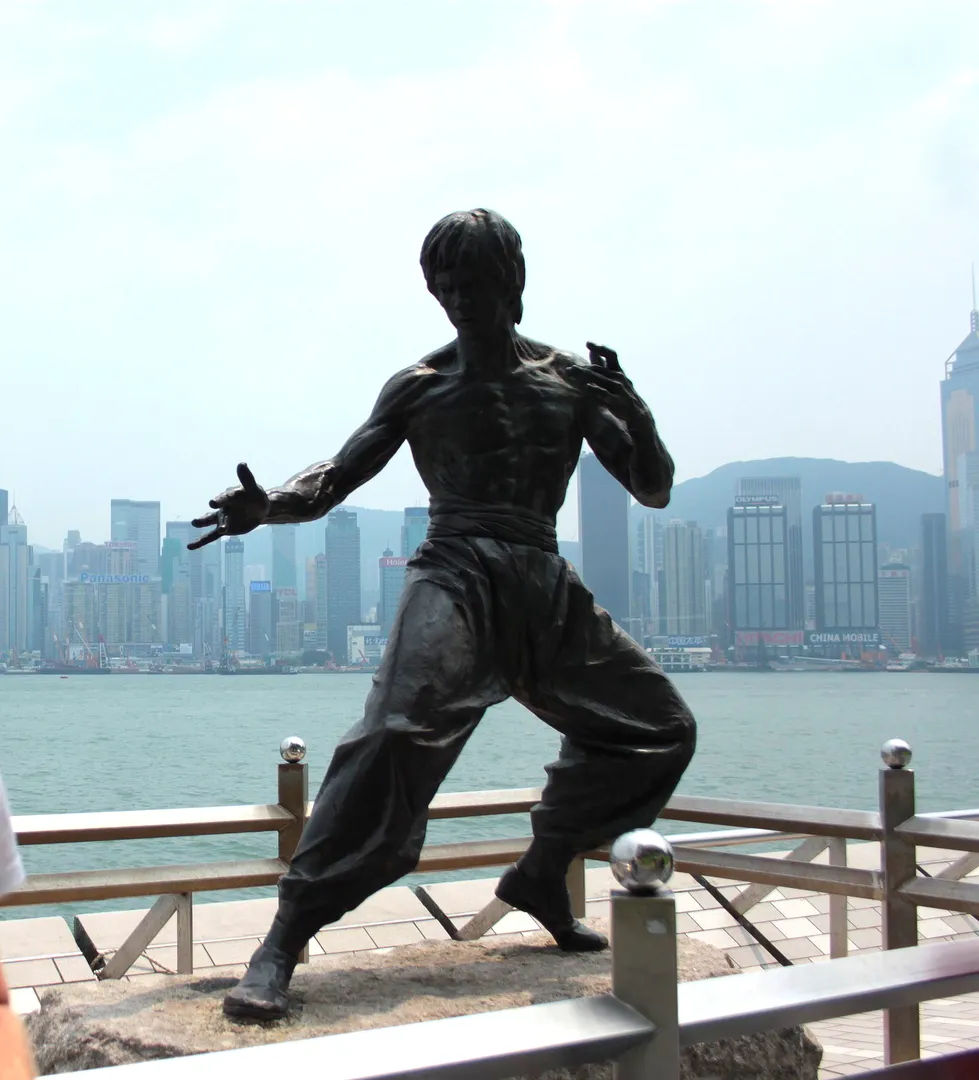 Posąg Bruce’a Lee na tle nowoczesnych wieżowców Hongkongu