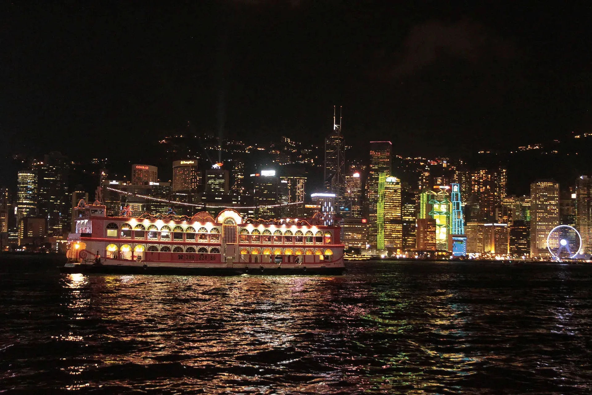 Duży statek z czerwonymi żaglami płynący nocą po wodach Hongkongu