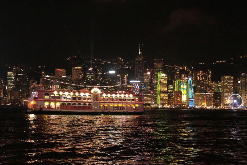 Duży statek z czerwonymi żaglami płynący nocą po wodach Hongkongu